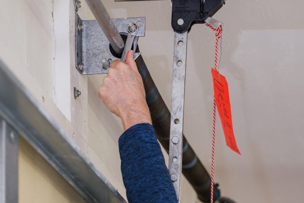 Man repairing electric garage door coiled tension spring. Instal Man repairing electric garage door coiled tension spring. Instal